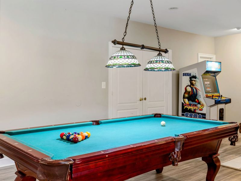 Game Room - A massage chair, vintage Sega arcade cabinet, and pool table anchor the entertainment level.