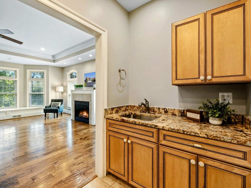 Primary Suite - A wet bar with granite counters and a sink sits between the bedroom and bath for added convenience.