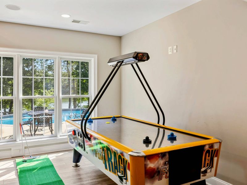 Game Room - Air hockey table and mini golf putting green by the window, with the pool deck just outside.