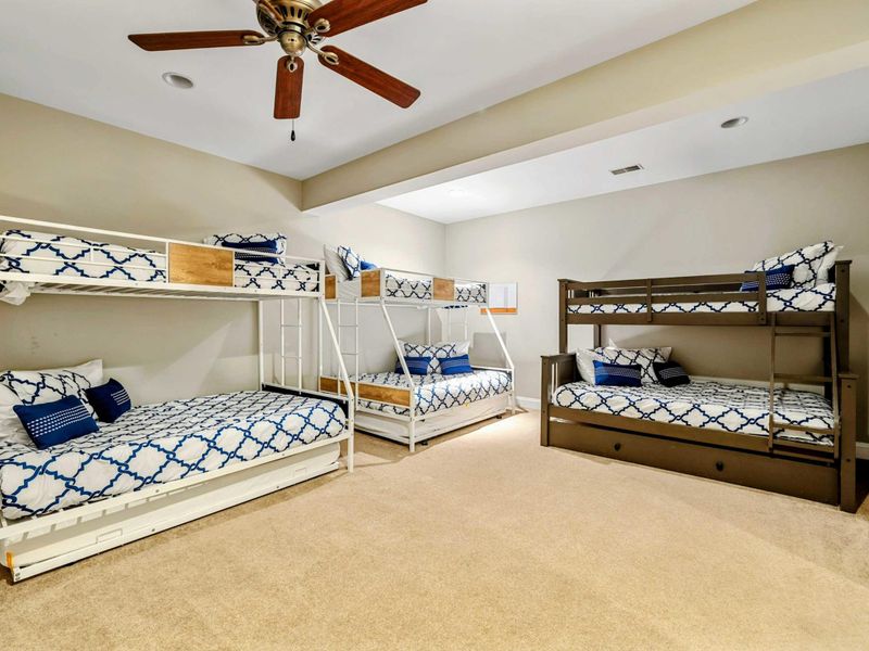 Bunk Room - Three bunk beds (two twin-over-full, one twin-over-twin with trundle) sleep the whole crew in coordinated blue-and-white bedding.