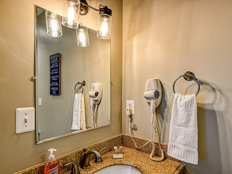 Lake Level Bath - A single vanity with granite counter, hair dryer, and industrial-style light fixtures.