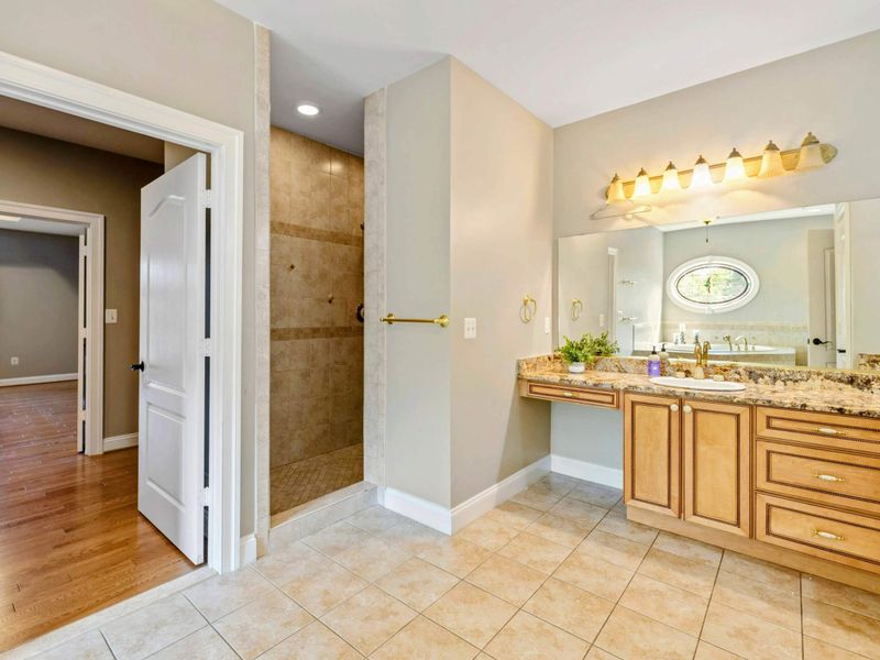 Primary Bath - The walk-in shower with vanity and tub visible through the doorway, connecting to the bedroom beyond.