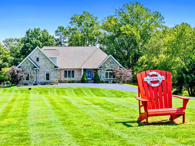 Exterior - A giant red Adirondack chair on the front lawn, perfect for group photos with the stone home behind.