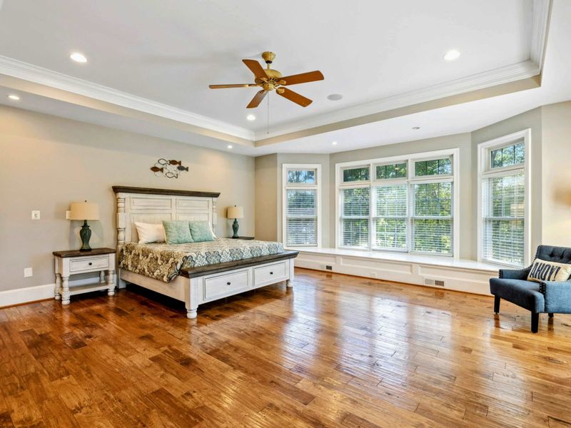 Primary Suite - A farmhouse king bed, bay window bench, and hardwood floors throughout the generous room.