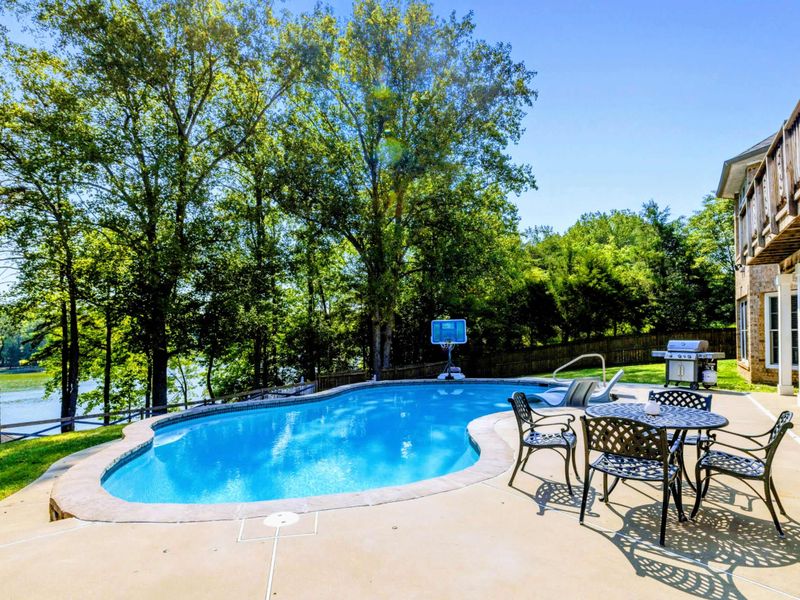 Pool - Patio seating overlooks the pool, with glimpses of the lake through the trees beyond.