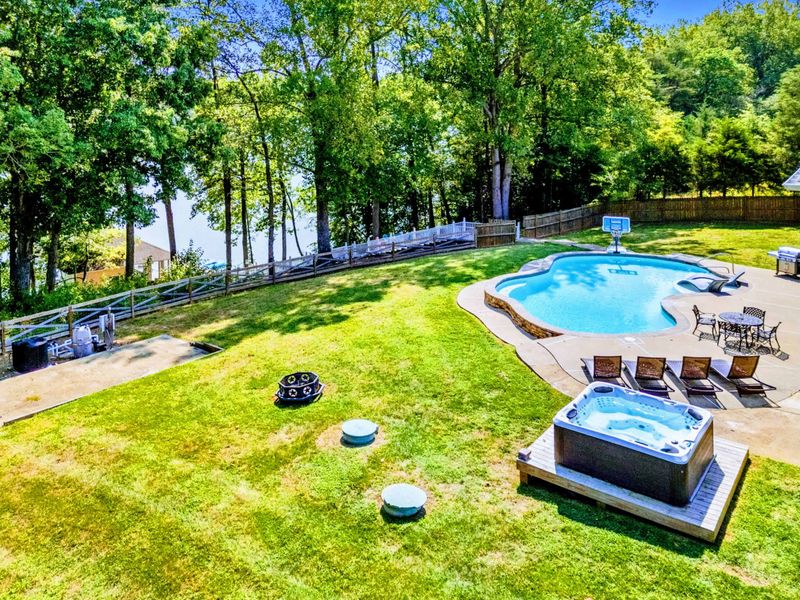 Backyard - An aerial view captures the full backyard: pool, hot tub, fire pit, and a path winding down to the lake.