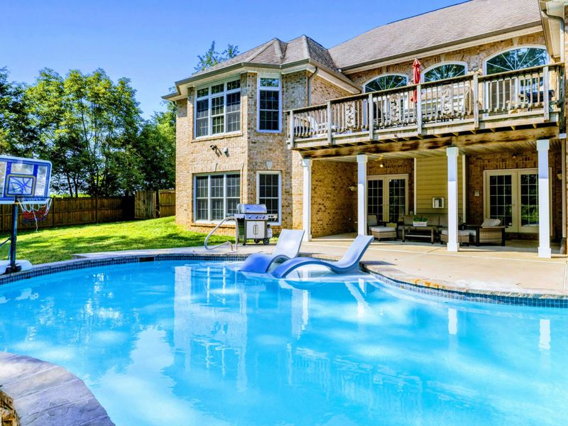 Pool - Patio seating and the basketball hoop pool from another angle, with the house and deck rising behind.