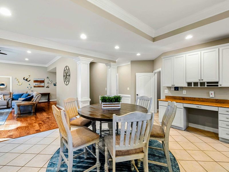 Breakfast Nook - A round table and built-in desk area connect the kitchen to the living room, with the main dining room visible beyond.