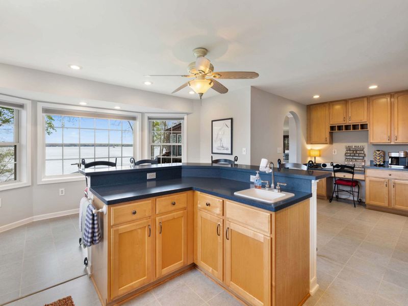 A spacious, well-lit kitchen with modern appliances, blue countertops, and a panoramic lake view