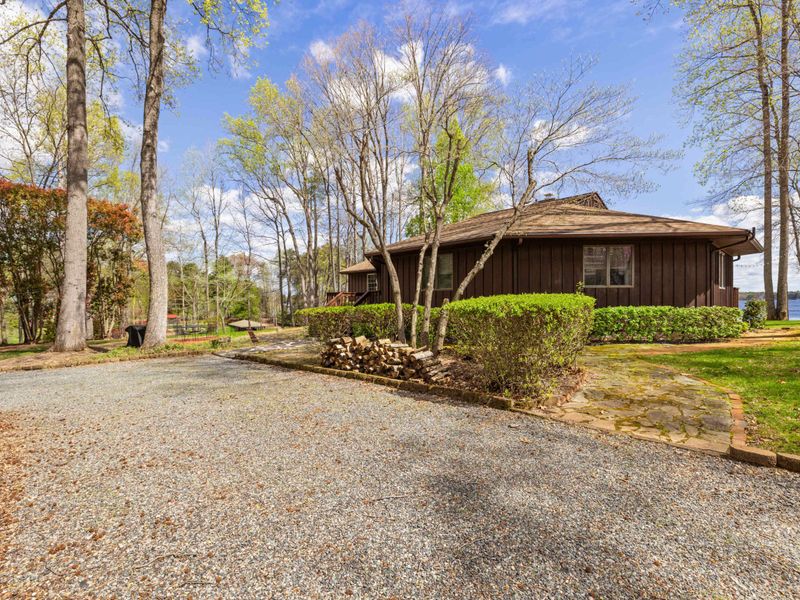 A cozy lakeside home with a front porch and stone walkway, set among tall trees with lake views