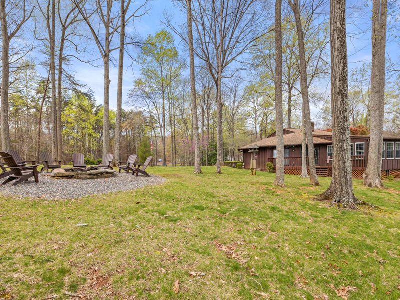 An inviting outdoor fire pit surrounded by wooden Adirondack chairs set in a tranquil forest clearing