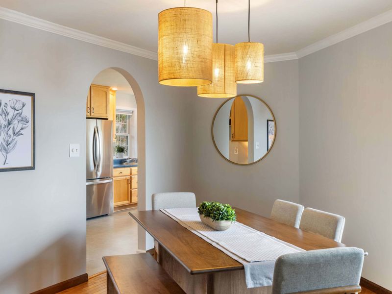 Chic dining space with a natural wood table, ambient lighting, and balcony access offering a tranquil forest backdrop