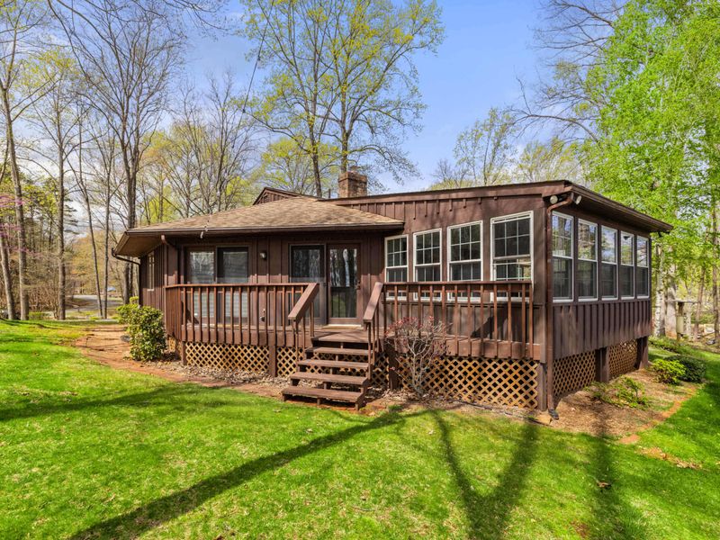 Charming woodland cabin with a sunroom and deck, offering a cozy retreat amid the tall trees