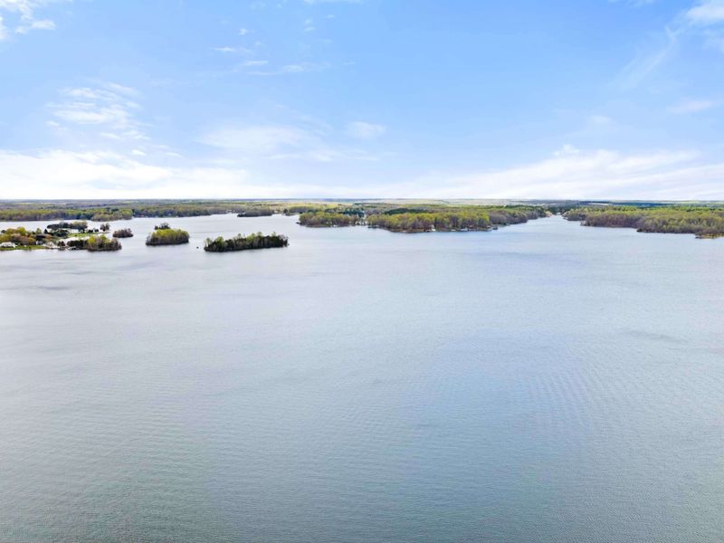 Aerial view of a vast, serene lake dotted with lush green islands and surrounded by a tranquil landscape
