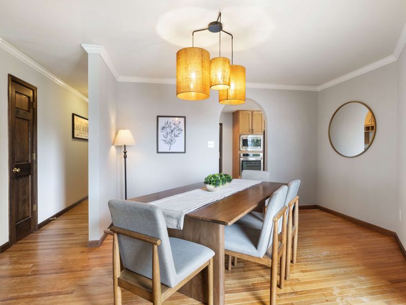 Chic dining space with a natural wood table, ambient lighting, and balcony access offering a tranquil forest backdrop
