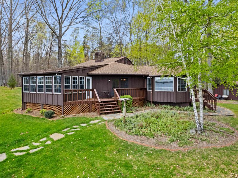Charming woodland cabin with a sunroom and deck, offering a cozy retreat amid the tall trees