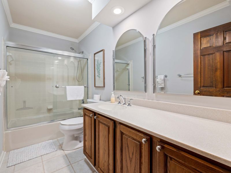 A pristine bathroom featuring a large vanity, mirror, and full bathtub with a shower