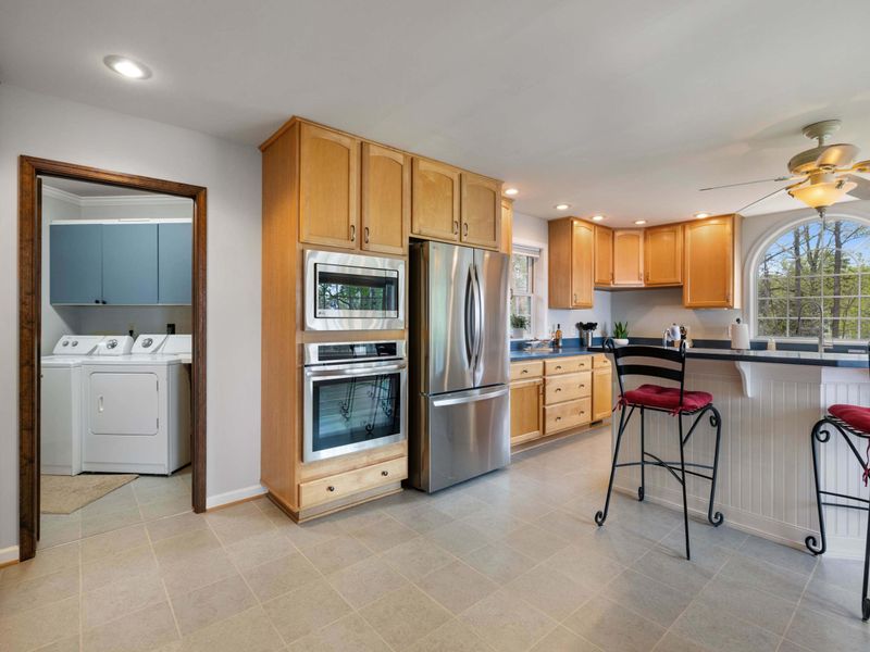A spacious, well-lit kitchen featuring modern appliances and a cozy breakfast bar with lake views