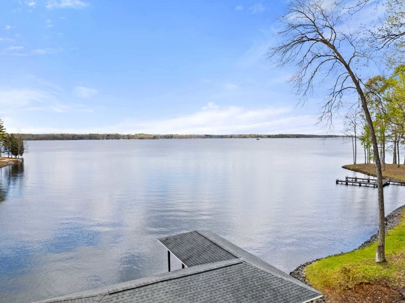 This is an idyllic lakeside vista offering a vast expanse of calm waters edged by gentle woodlands