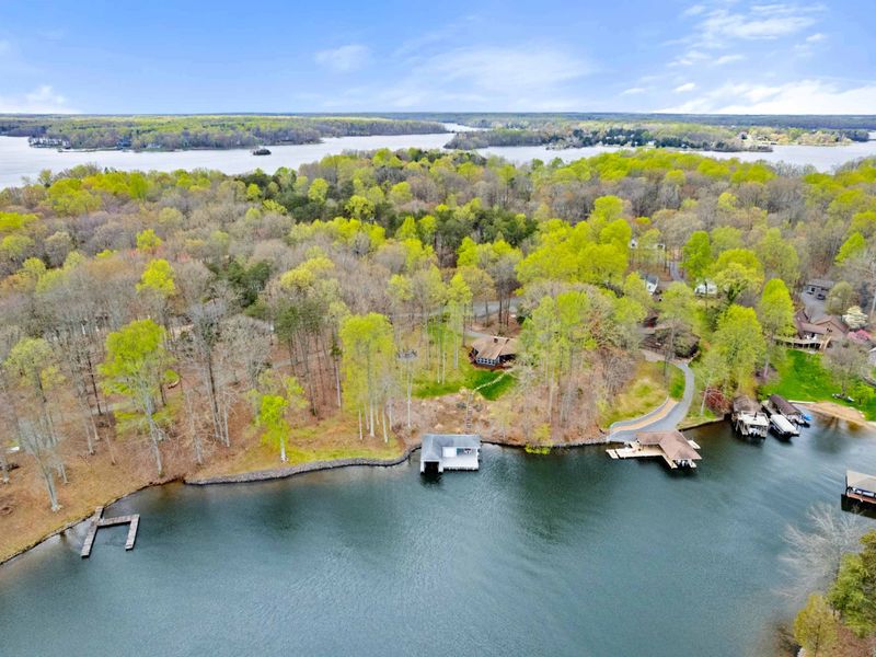 An aerial snapshot captures a secluded cabin retreat by a serene lake, complete with a private dock amidst a forested landscape