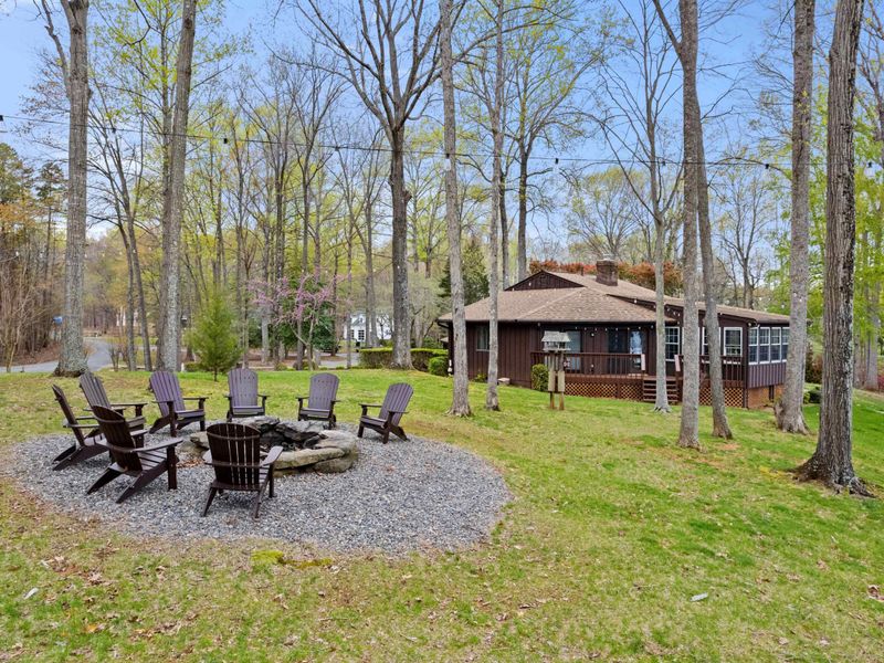 An inviting outdoor fire pit surrounded by wooden Adirondack chairs set in a tranquil forest clearing