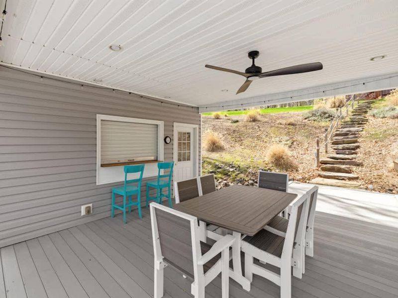 Cozy and inviting covered deck space with comfortable seating and a rustic stone stairway leading into nature