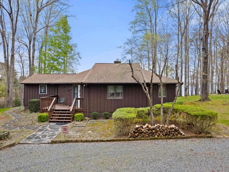 A cozy lakeside home with a front porch and stone walkway, set among tall trees with lake views