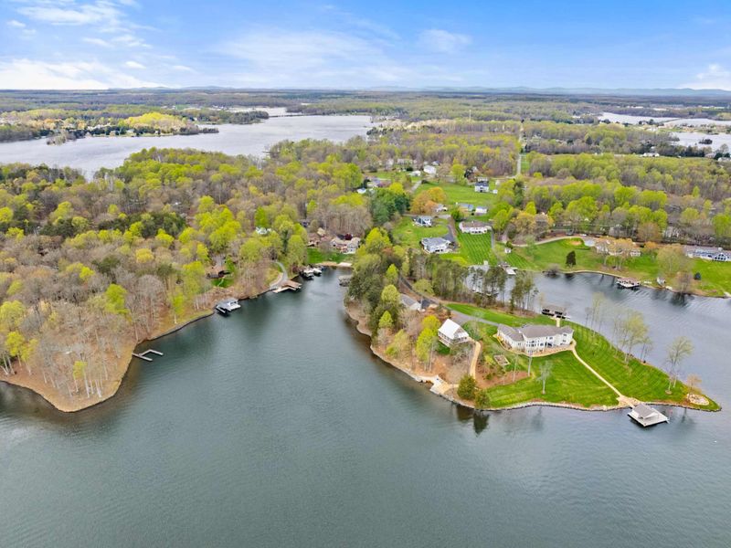 Sweeping aerial view of a lush peninsula with elegant homes and private docks on a vast and serene lake