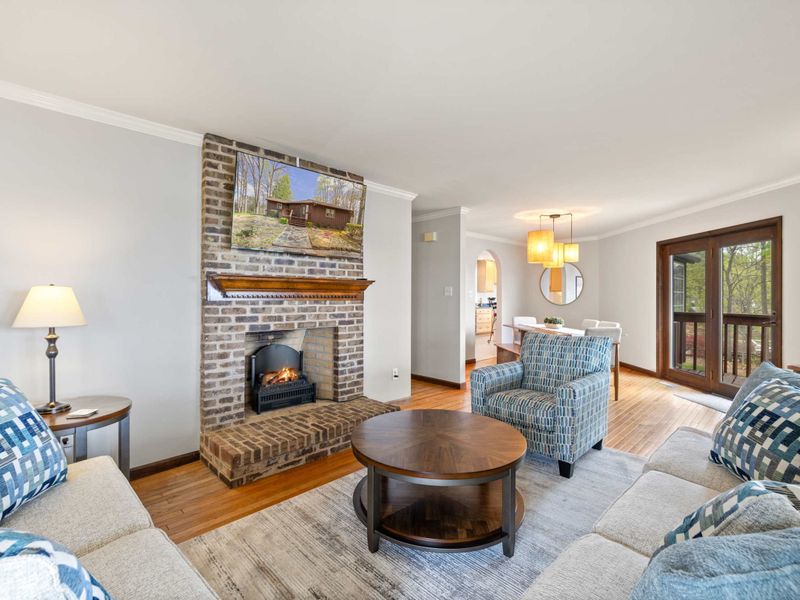 Bright and airy living space with comfortable seating, a brick fireplace, and views of the outdoors through large windows, perfect for a peaceful retreat
