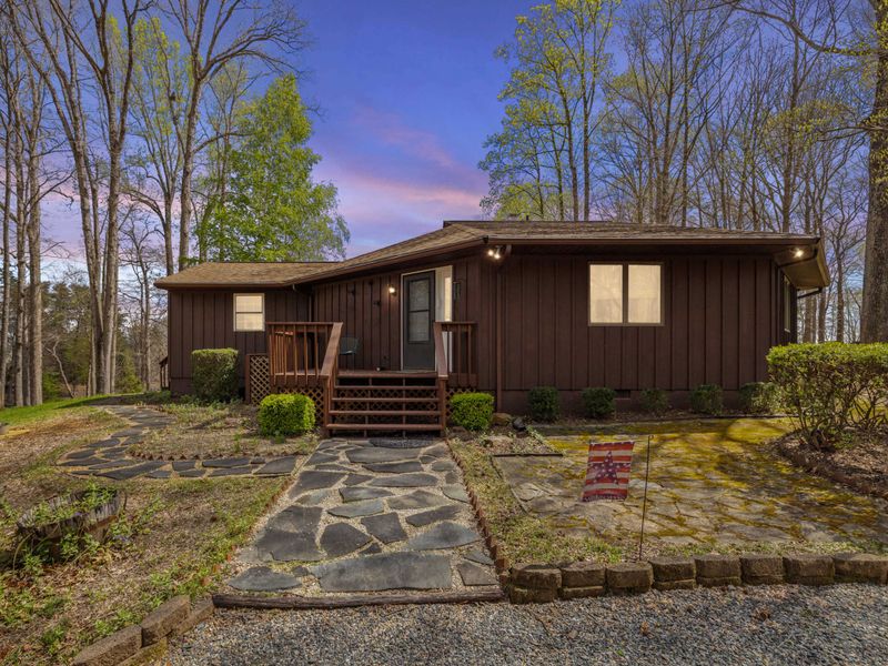 Quaint cabin with a flagstone walkway set in a serene woodland landscape, offering a tranquil retreat.