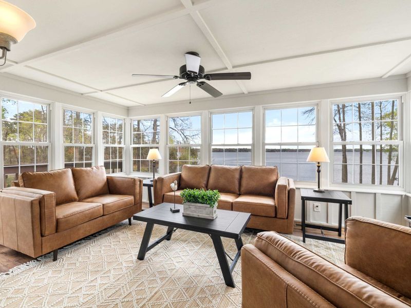 Sunlit cozy living space with comfortable seating and large windows offering a stunning lake view