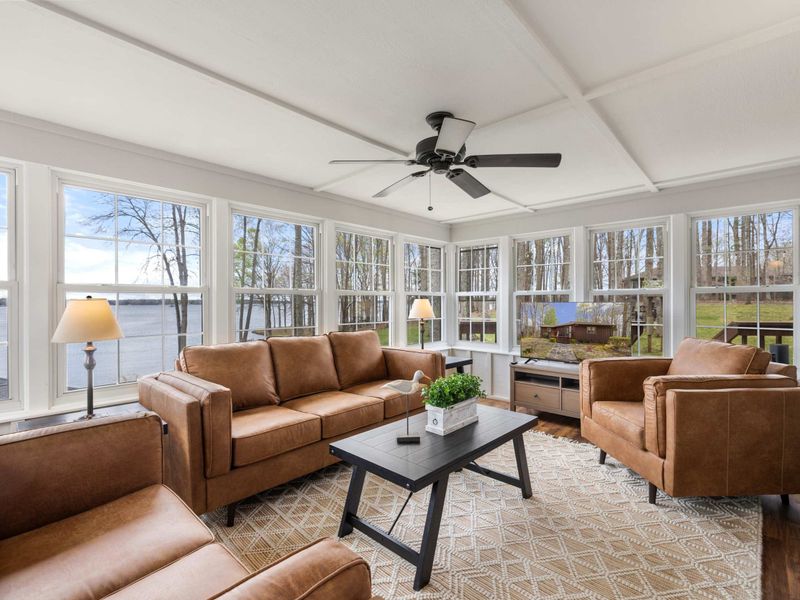 Sunlit cozy living space with comfortable seating and large windows offering a stunning lake view
