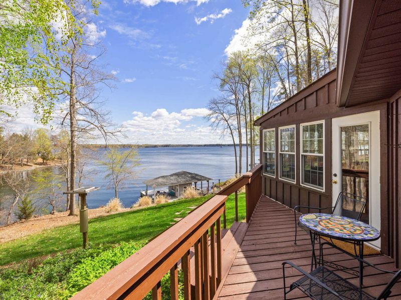 A scenic cabin deck with a view of the expansive lake and surrounding lush greenery, perfect for a peaceful morning coffee