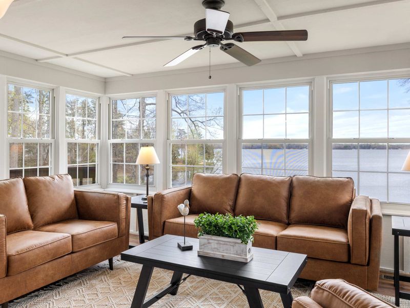 Sunlit cozy living space with comfortable seating and large windows offering a stunning lake view