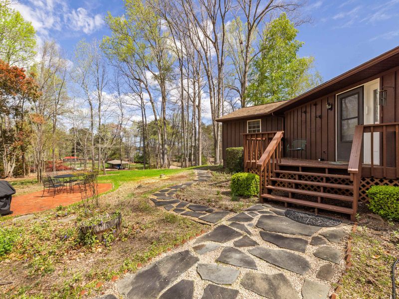 Quaint cabin with a flagstone walkway set in a serene woodland landscape, offering a tranquil retreat.