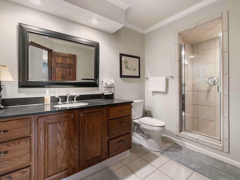 A clean and sophisticated bathroom with a large mirror, wood vanity, and a glass-enclosed shower