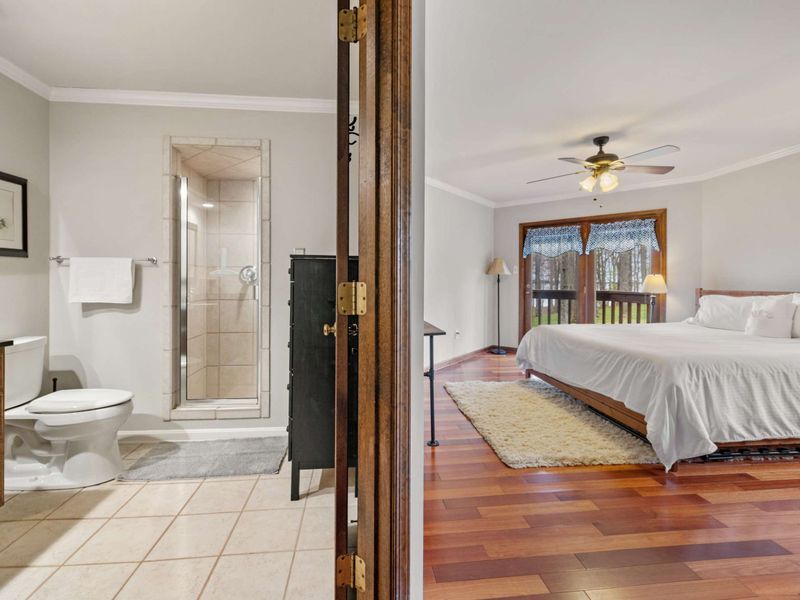 A spacious en-suite bedroom with gleaming hardwood floors and direct access to a modern bathroom