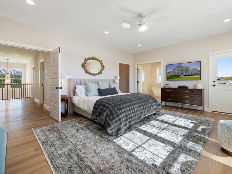 Primary Suite - The king bed framed by lake-view windows, a round mirror above the headboard keeping the space open.