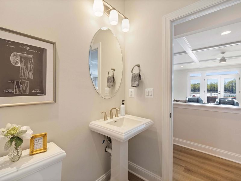Half Bathroom - A tidy powder room with a pedestal sink, framed art, and soft neutral finishes.