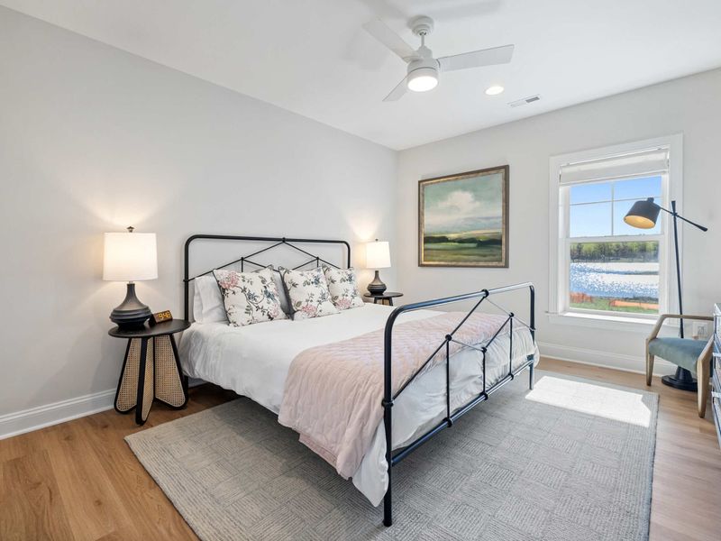 Bedroom 6 - A queen iron bed frame by the window, with a soft rug and nightstands on either side.