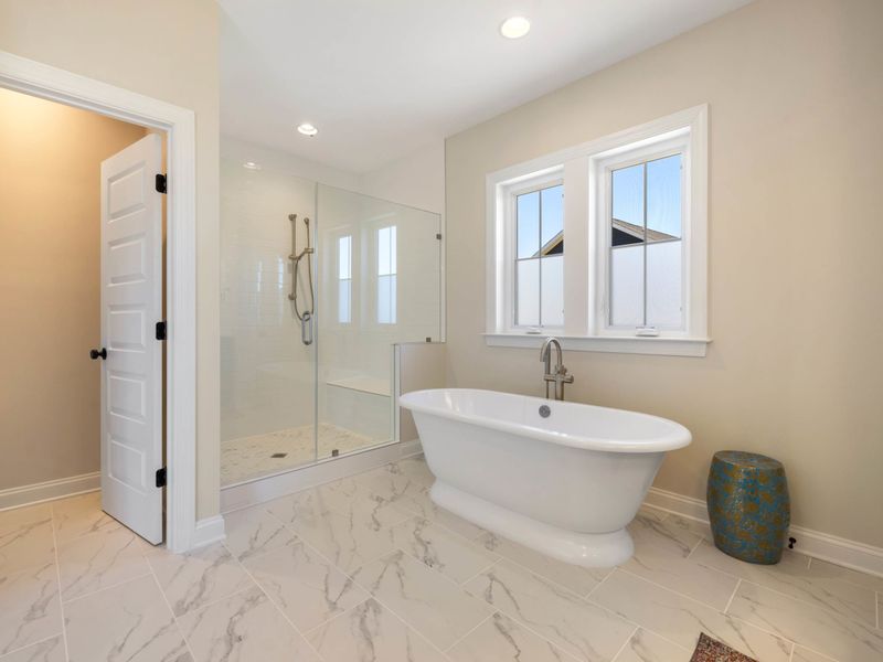Primary Suite - A freestanding soaking tub tucked beside a bright window, a spa moment built into the room.