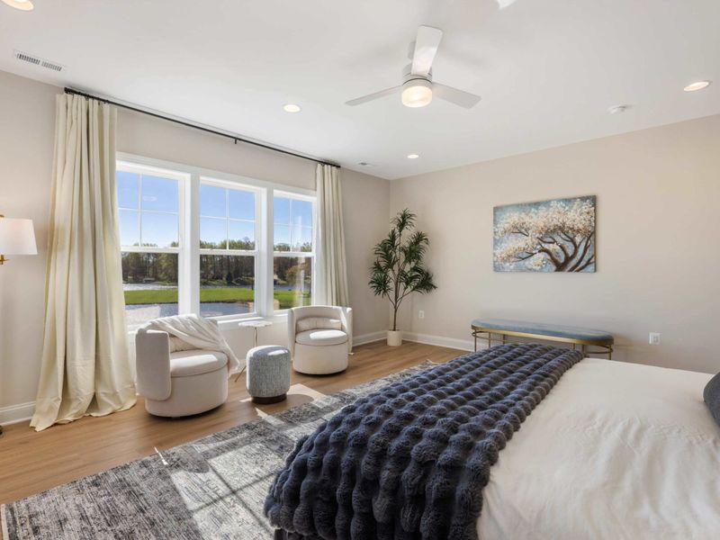 Primary Suite - Another angle of the primary bedroom, sitting area and lake windows lit by midday light.