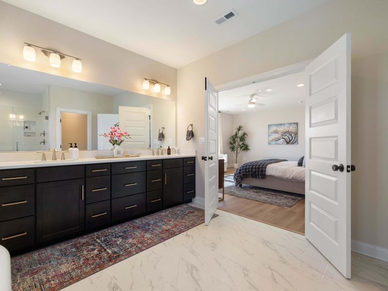 Primary Suite - Inside the en-suite, dual vanities and a wide mirror with a peek back into the bedroom.