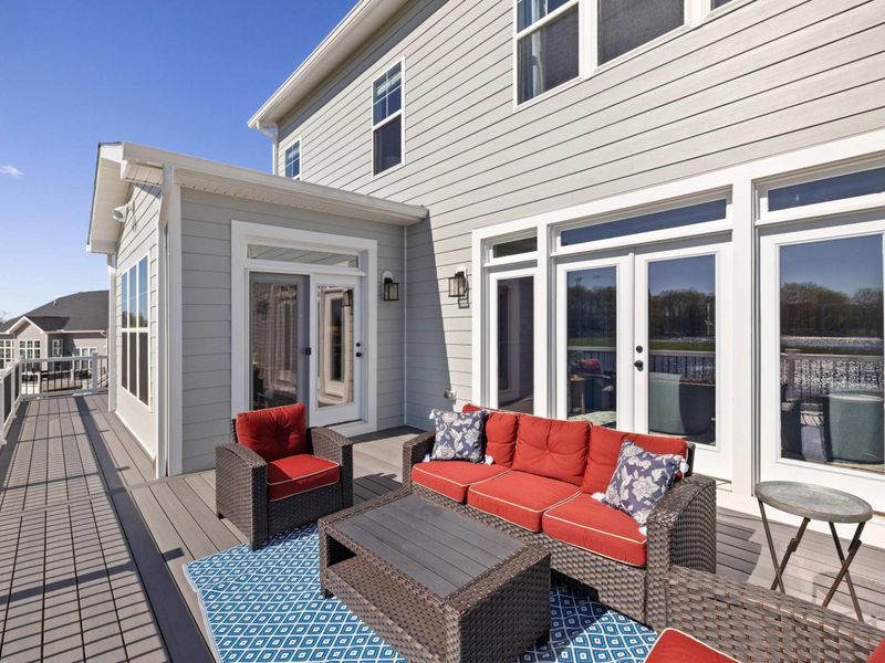 Patio - Red chairs and a rug on the deck, tucked into the shade with the lake right over the railing.