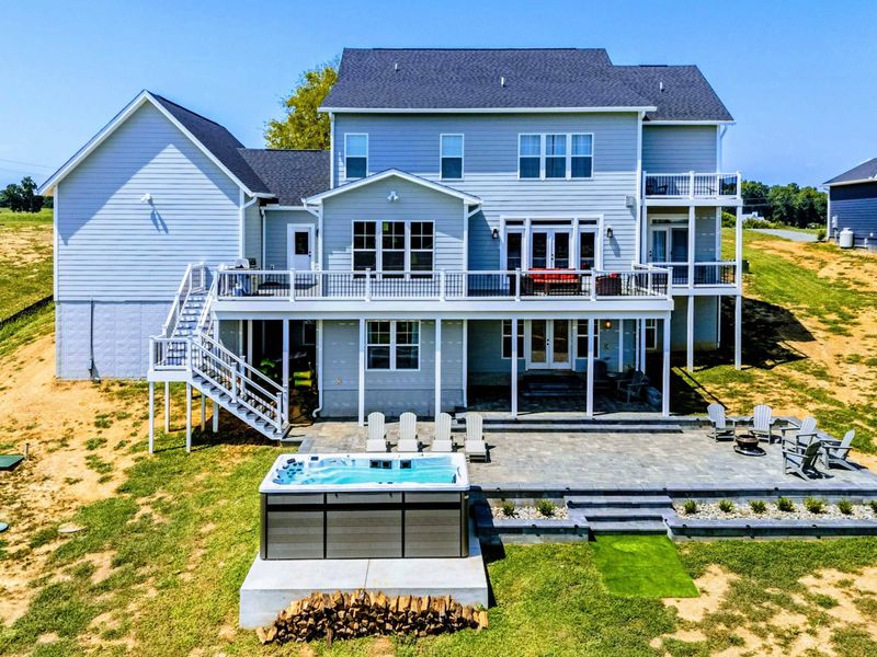 Backyard - High-angle view of the full home, showing the outdoor living zones layered between house and water.