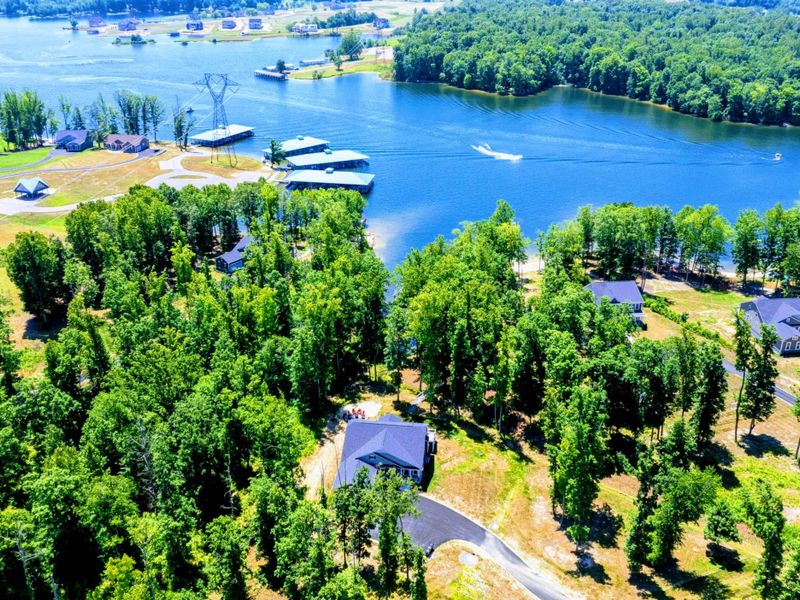 Aerial view of a lakeside community surrounded by lush greenery, with direct water access and boating facilities