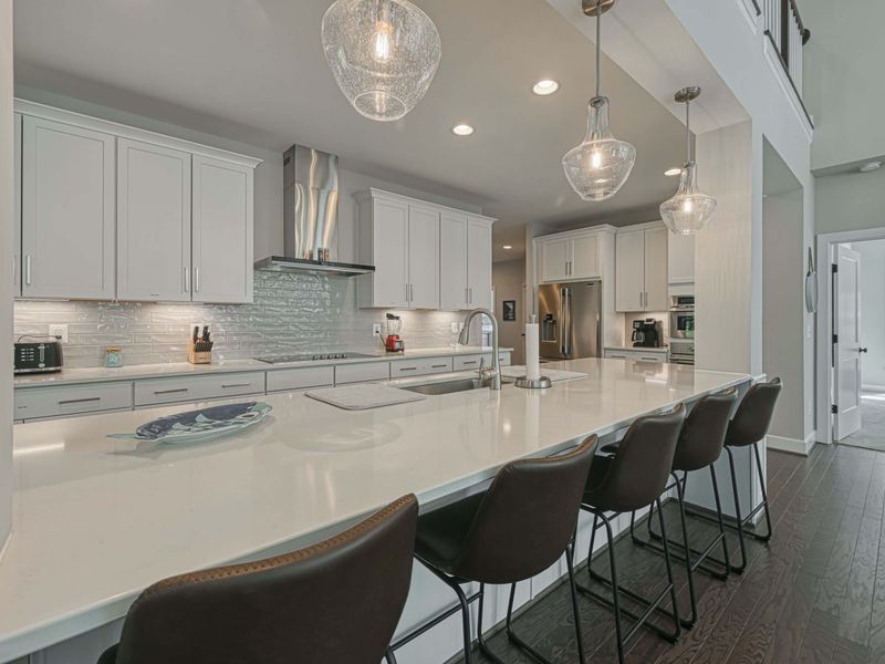 Modern kitchen with a large island, elegant lighting, and high-end appliances.