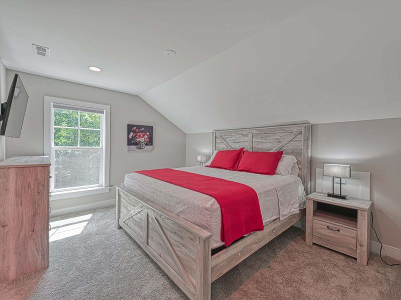Charming bedroom with a king-size bed, vibrant red accents, and a flat-screen TV