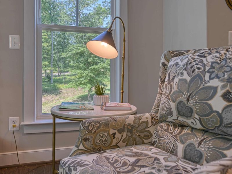Cozy reading nook with a comfortable armchair and a view of the lush greenery outside.