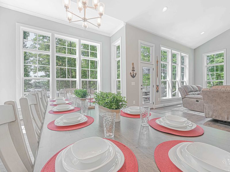 Bright and inviting dining area with large windows, a set table, and views of the surrounding greenery.